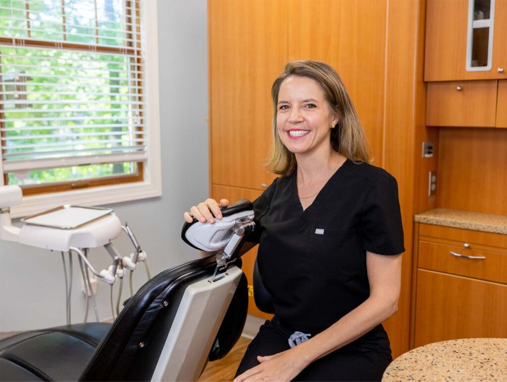 Dr. Liz leaning on a dental chair