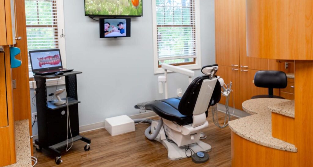 patient room with a dental chair, tv, and montior