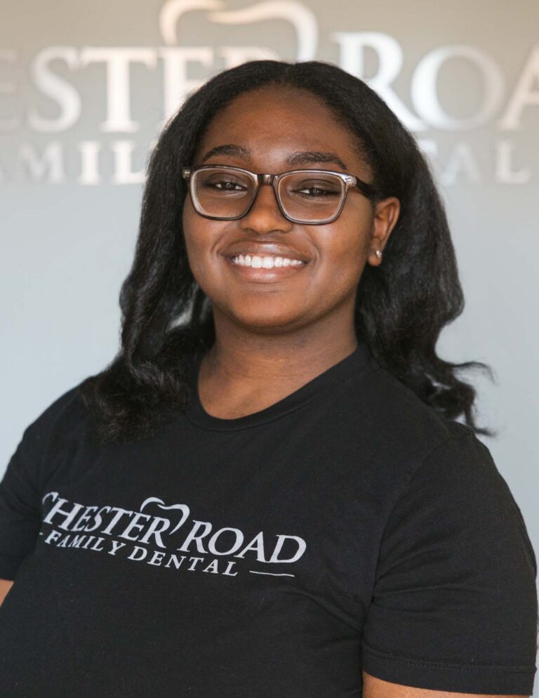 Headshot of Alexa - Dental Assistant wearing a black shirt with a Chester Road Family Dental logo and also the background.