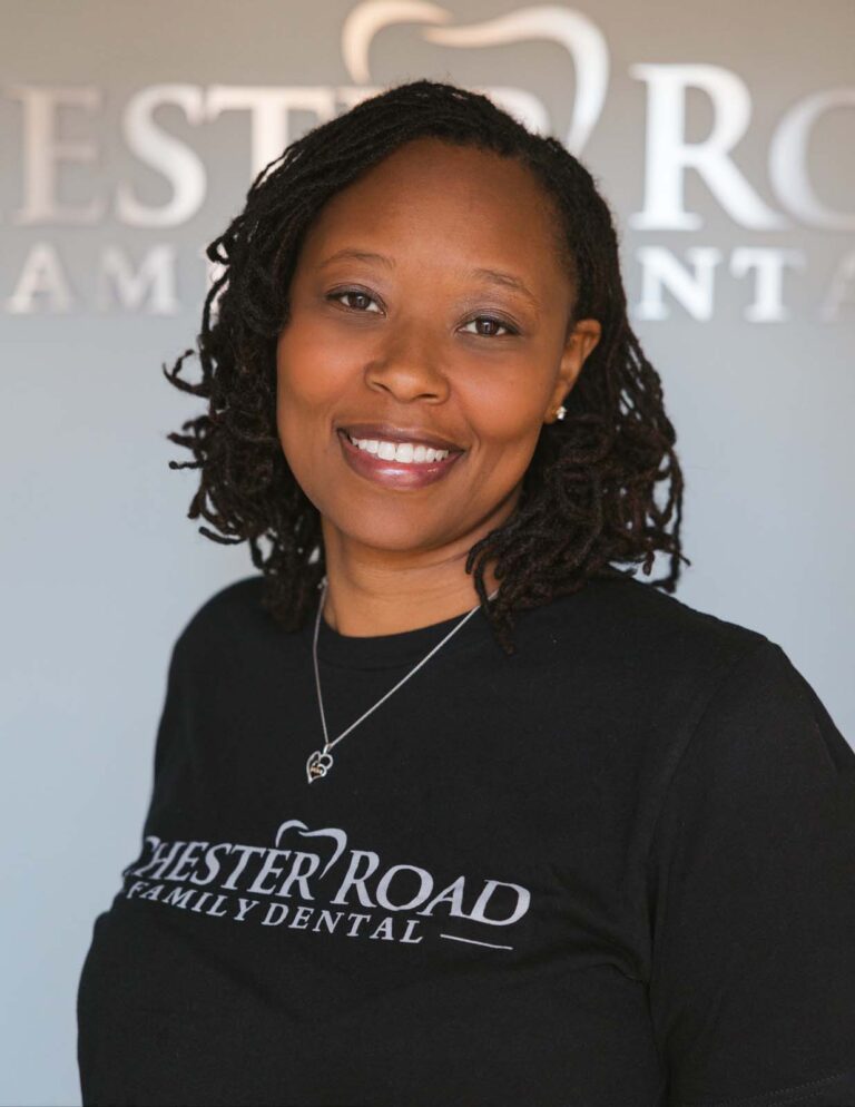 Headshot of Brandi - Dental Hygienst wearing a black shirt with a Chester Road Family Dental logo and also the background.
