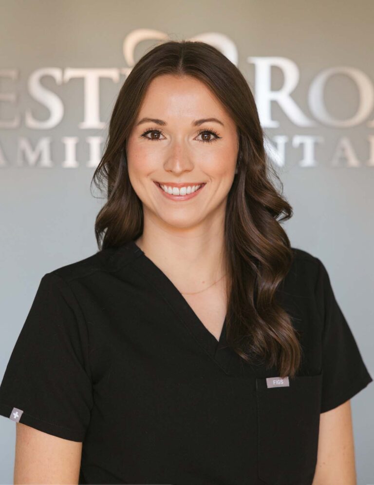 Headshot of Dr. Christine Gauss wearing a black scrubs with a background of Chester Road Family Dental.