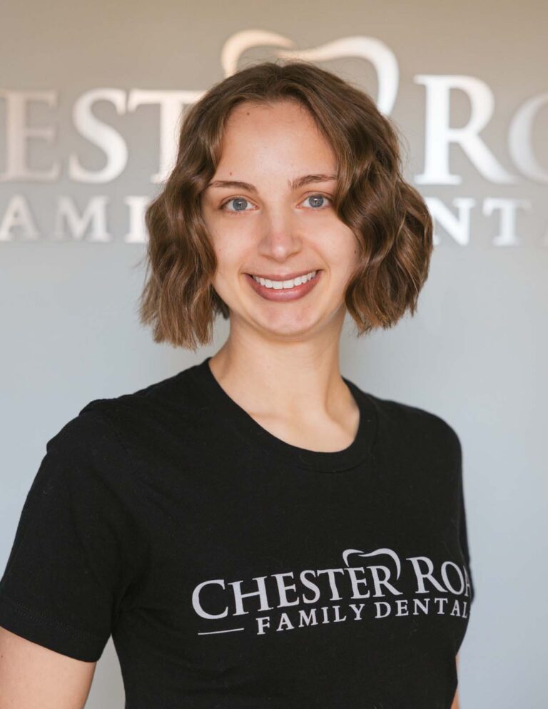Headshot of Jessica - Dental Hygienist wearing a black shirt with the logo of Chester Road Family Dental in it and same in the background.