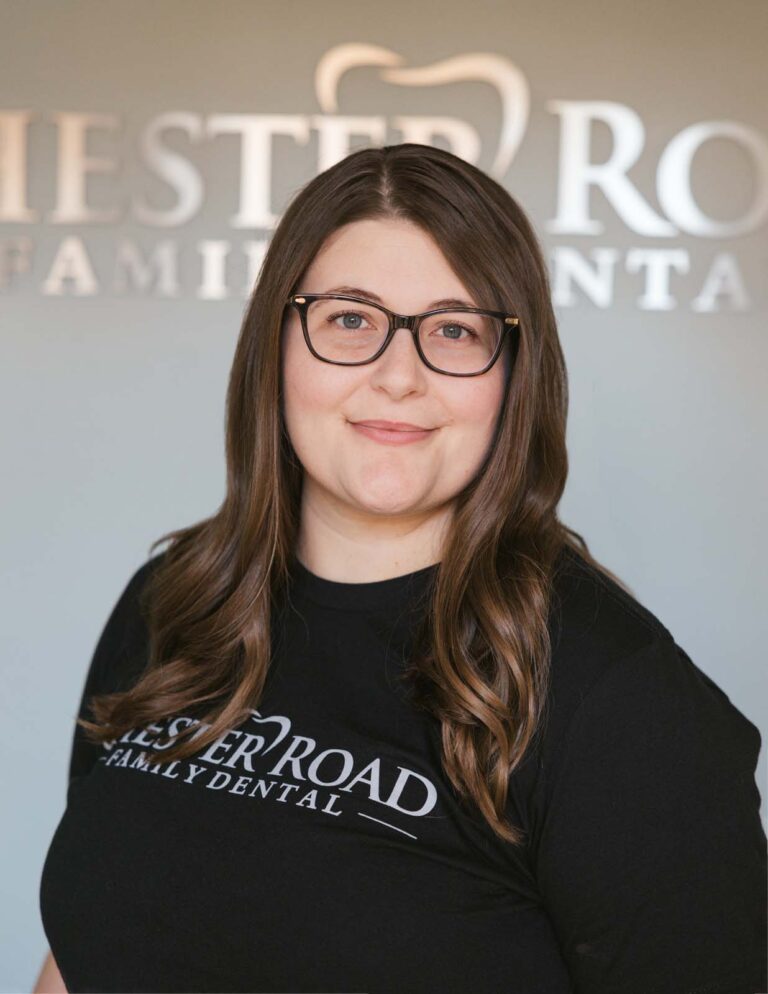 Headshot of Lyndsay - Dental Assistant, wears a black shirt with "CHESTER ROAD FAMILY DENTAL" printed on the front. The background is the Chester Road Family Dental logo.